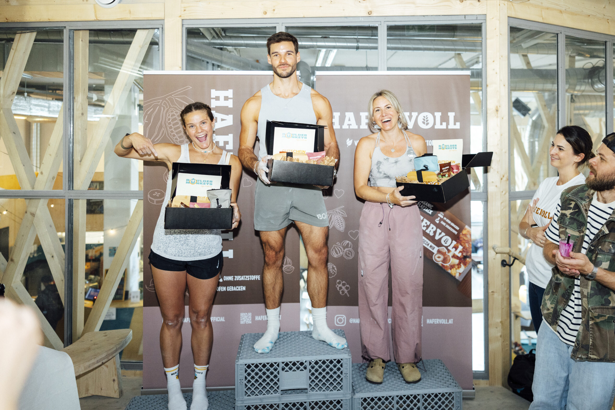 Ein Mann und zwei Frauen stehen auf einem Podest. Der Mann steht auf dem 1. Platz etwas oberhalb der Frauen. Alle drei halten eine Box mit HAFERVOLL Produkten in der Hand und lächeln in die Kamera.