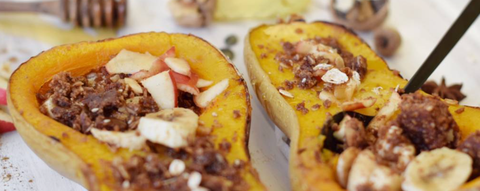Zwei Butternusskürbishälften gefüllt mit Bananenscheiben, Apfel und Schokolade