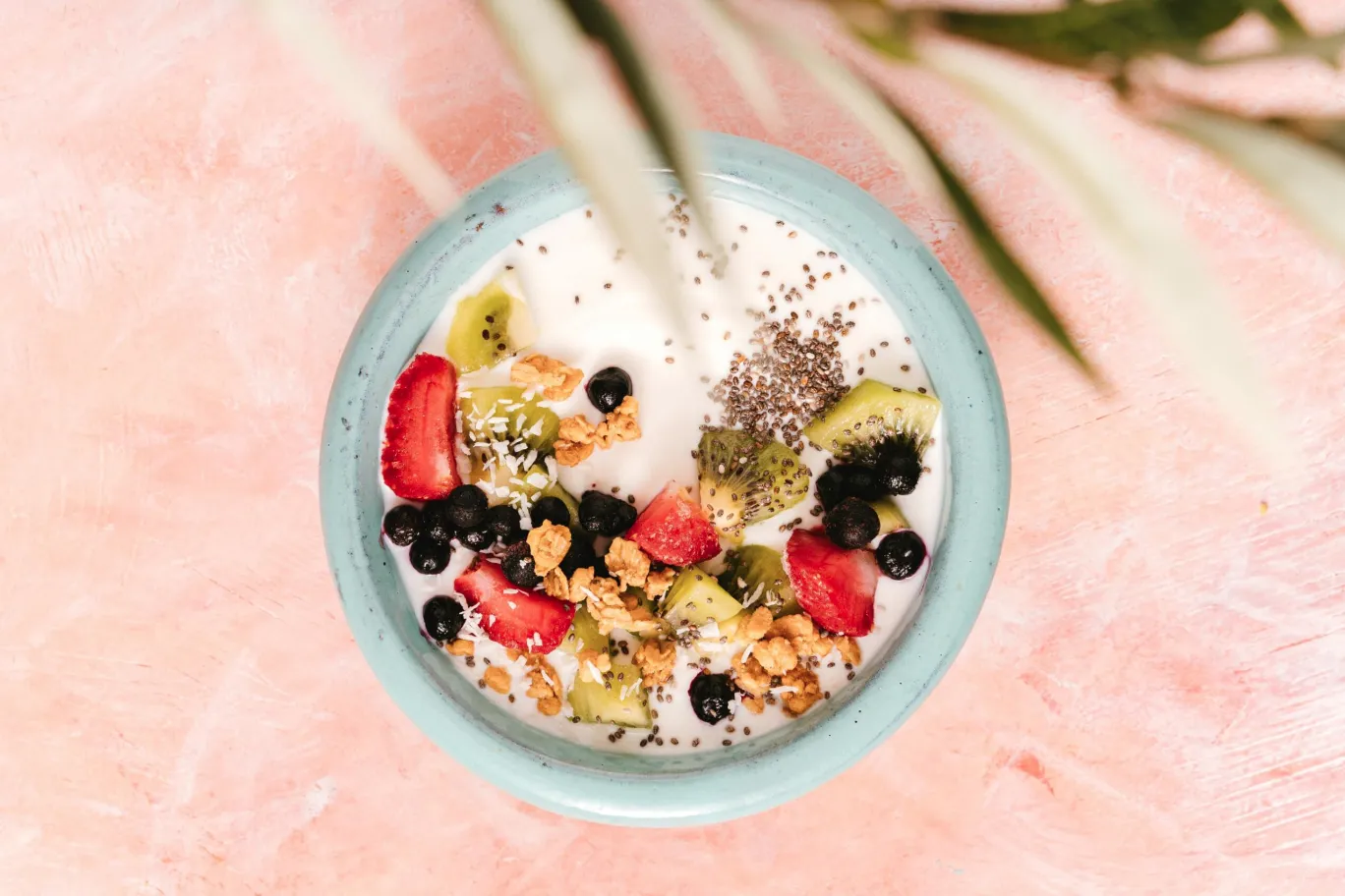 Eine Schüssel mit planzlichem Kokosjoghurt, Chia-Pudding, Kiwi, Erdbeeren, dem HAFERVOLL Flapjack Chia & Pistachio und Kokosraspeln.
