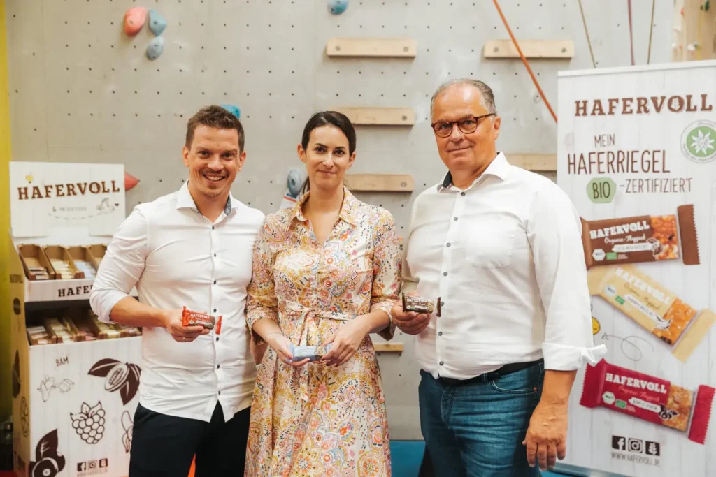 Mario Tlapak, Theresa Bichler und Thomas Gerdenitsch halten Hafervoll-Riegel in einer Kletterhalle